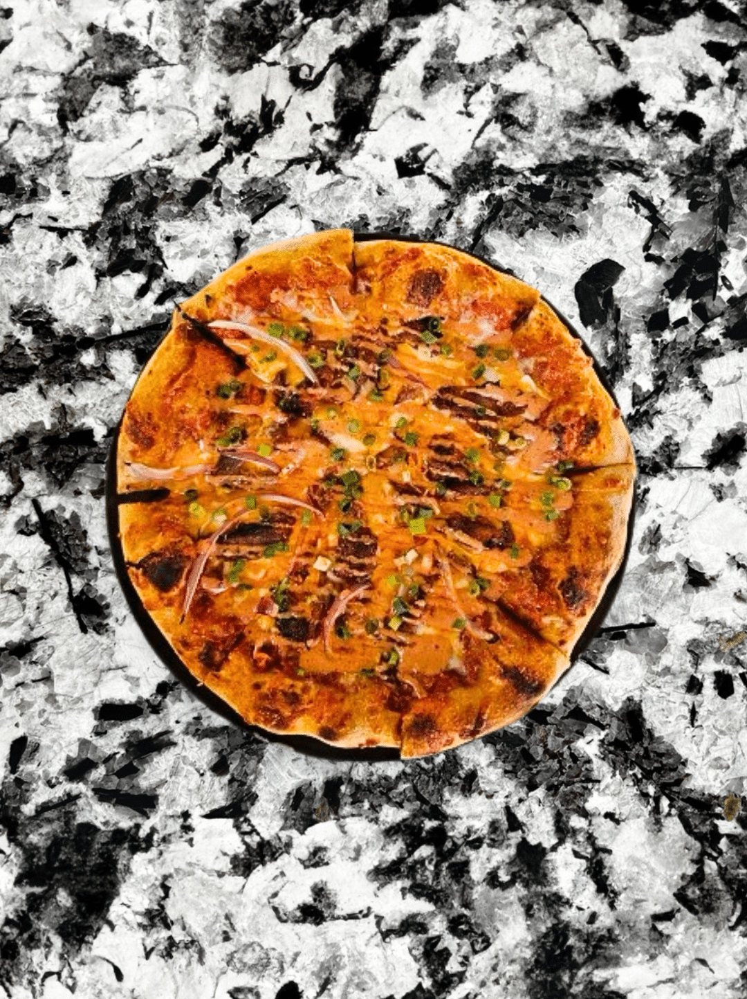 This pizza is made with Grandma's marinara, smoked cheddar, mozzarella, pulled BBQ pork spare ribs, red onions, scallions, sweet & spicy BBQ aioli.