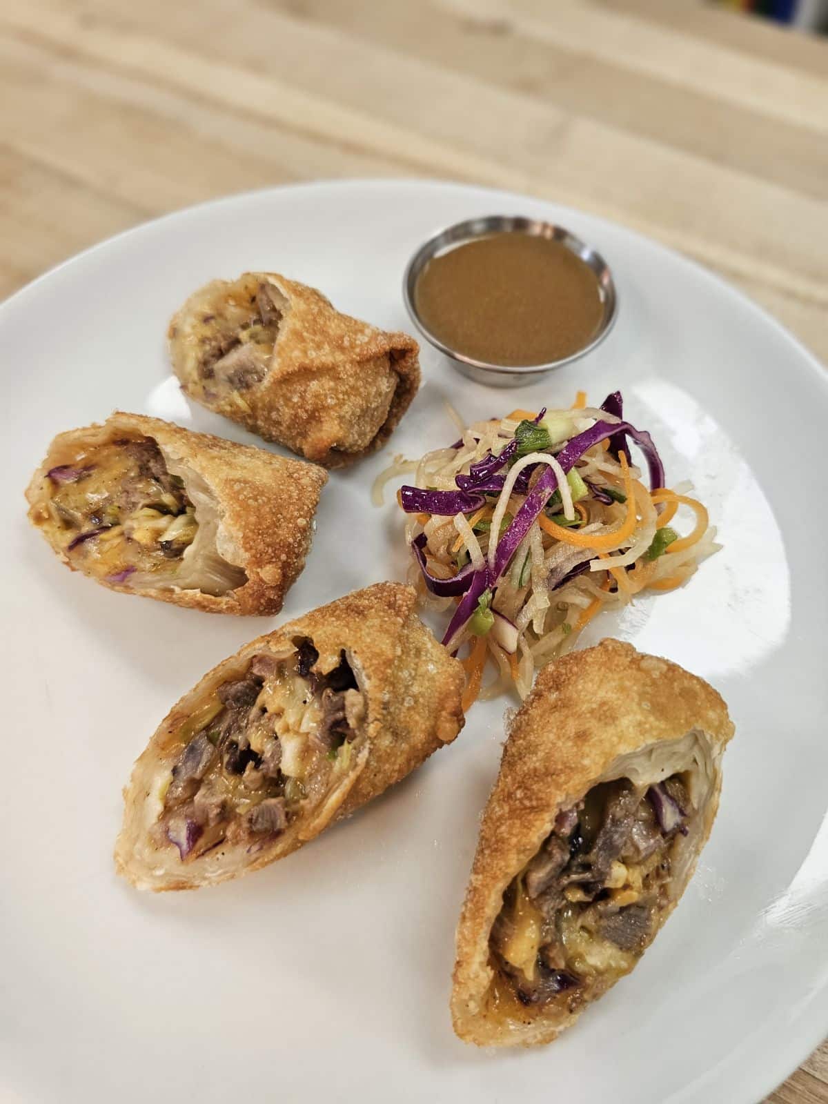 House-smoked High Plains heritage farms brisket, smoked gouda, caramelized onions and cabbage in a crispy egg roll, served with a radish and carrot salad and a side of maple jus.