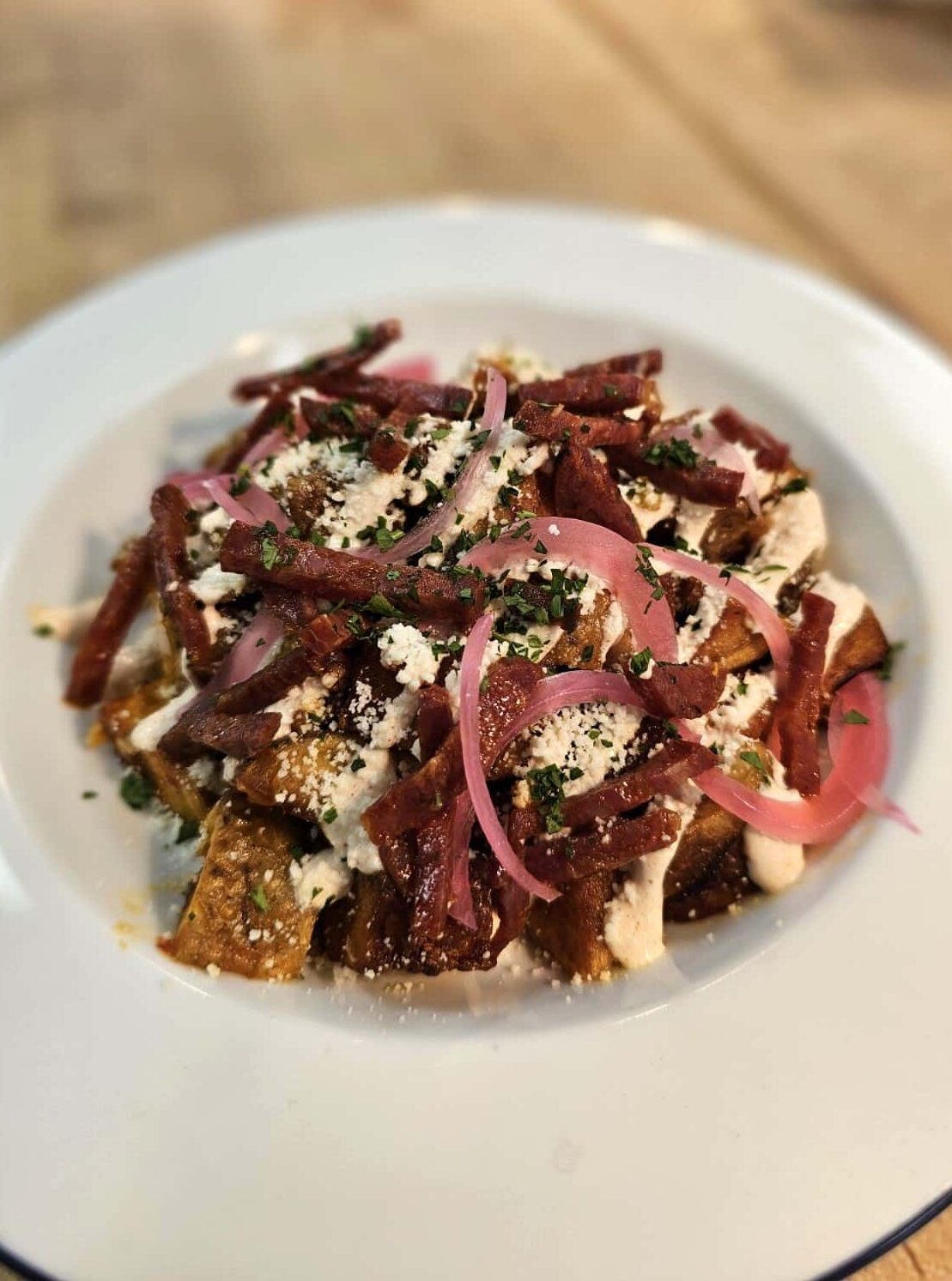 Crispy fried potatoes tossed in roasted garlic and Calabrian chile, Spanish chorizo, cotija cheese, smoked paprika sour cream, pickled red onion and fresh parsley.